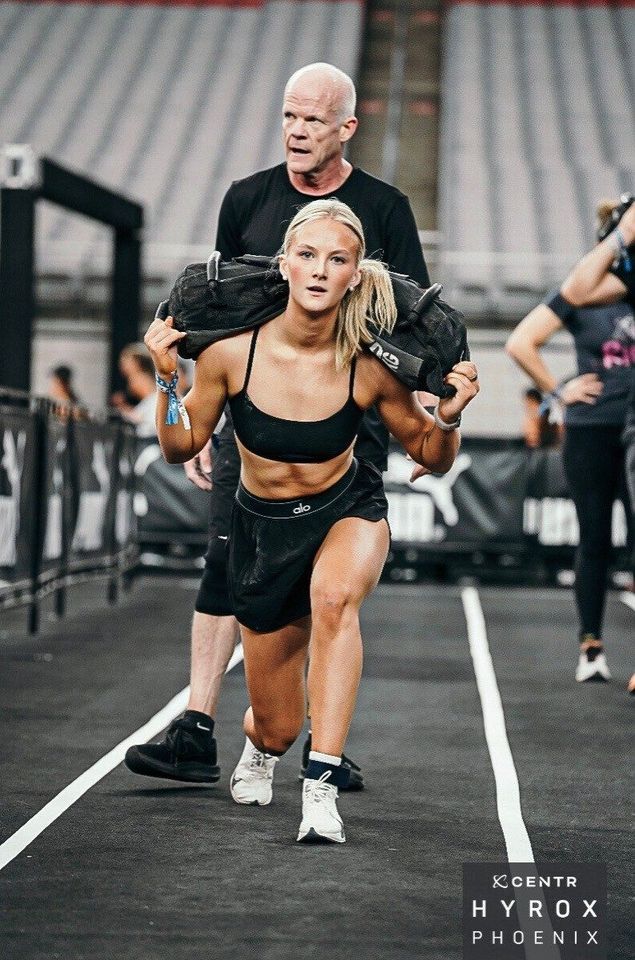 Callie, carrying a sandbag at a Hyrox race